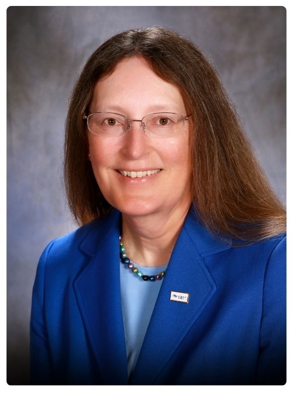 Formal portrait of Dr. Carmen Simone, president of Lake Region State College, wearing a blue blazer and glasses against a neutral studio background.