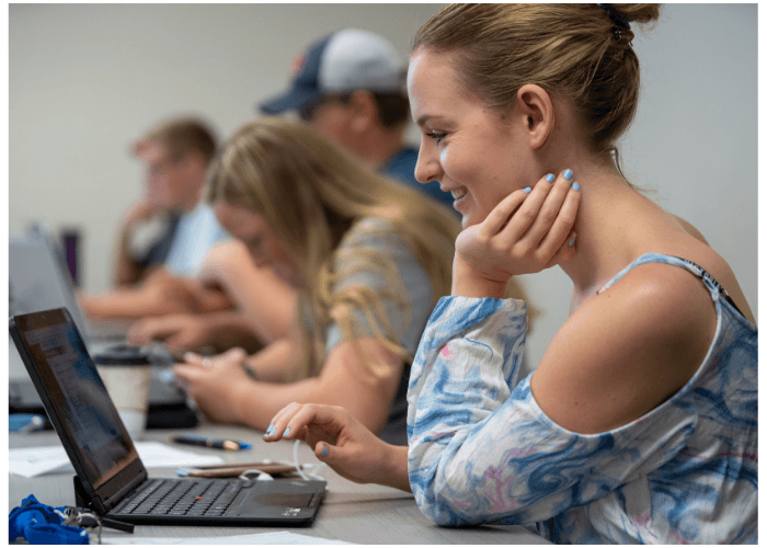 Student working on a computer in class alongside other Lake Region State College students.