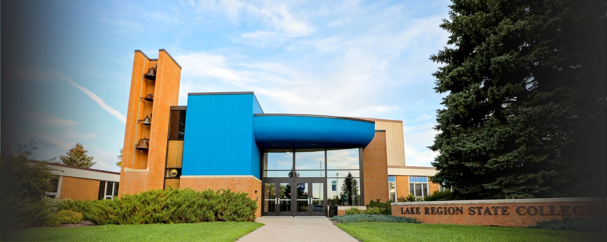 Lake Region State College campus building entrance with blue facade and brick college sign.
