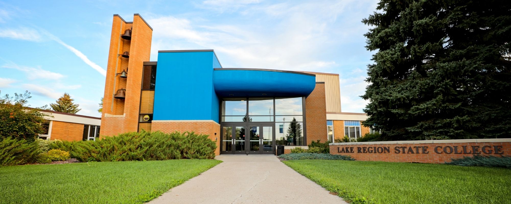 Lake Region State College campus building entrance with blue facade and brick college sign.