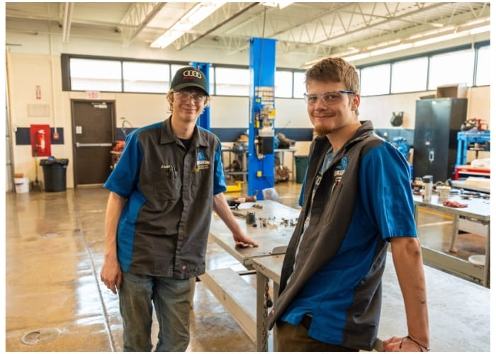 Two male students working in an automotive shop. 