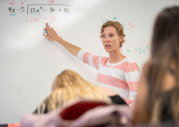 Female instructor pointing at a math problem. 