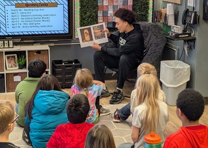 A student reading to a classroom. 