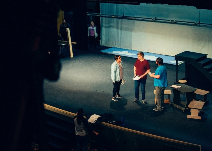 Picture of three students acting on stage. 