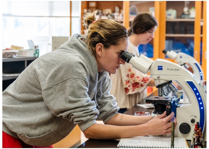 Graphic featuring student working in a biology classroom.
