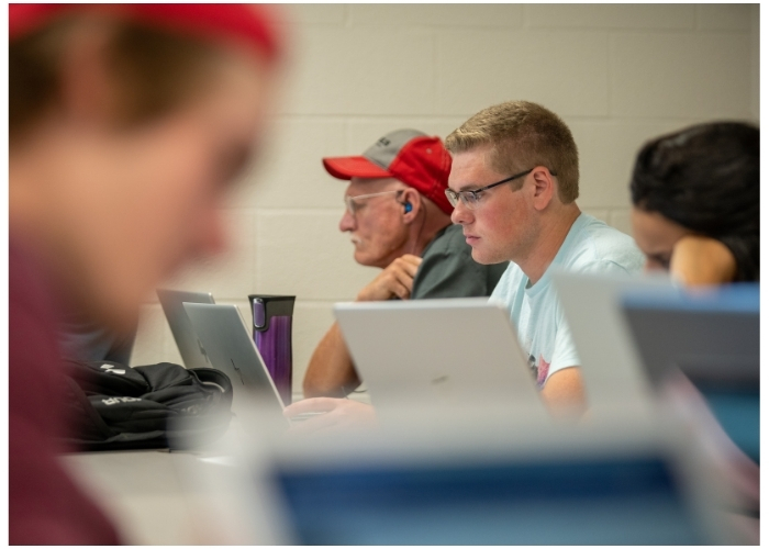 Lake Region State College student works on a laptop computer in a classroom setting.