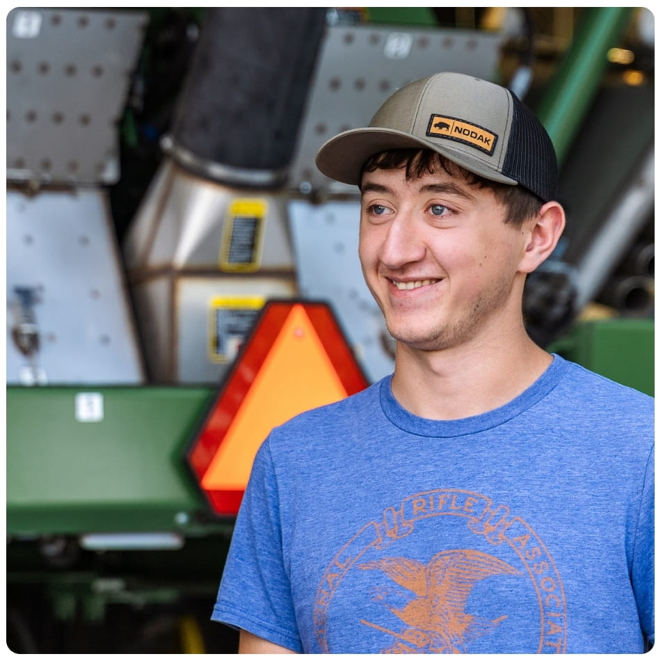Student in front of agricultural equipment. 