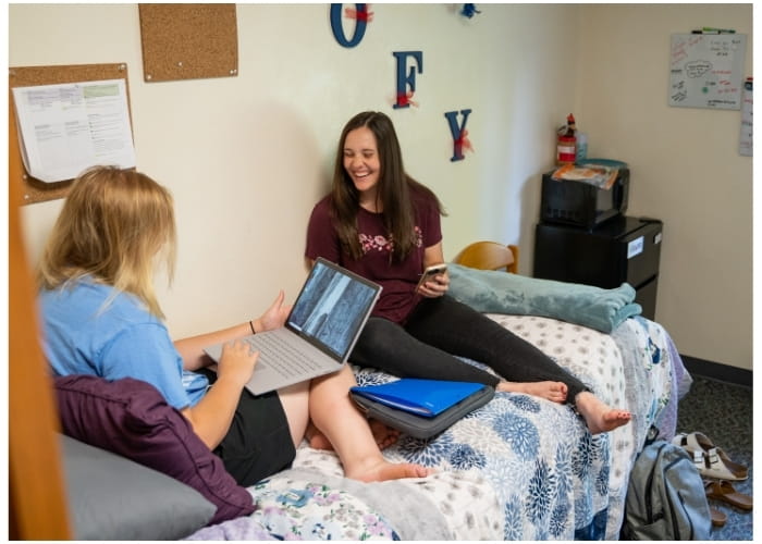 Two students sitting together in a dorm room. 