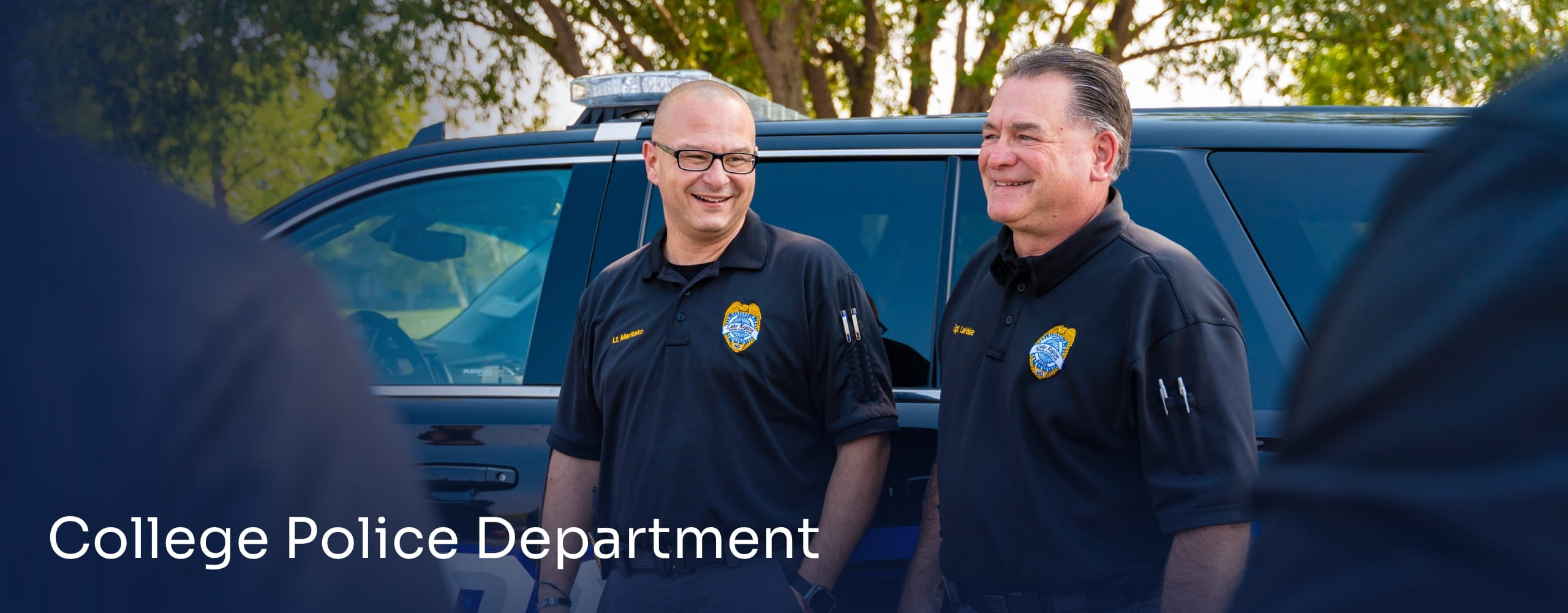 Campus police officers standing near a patrol vehicle.
