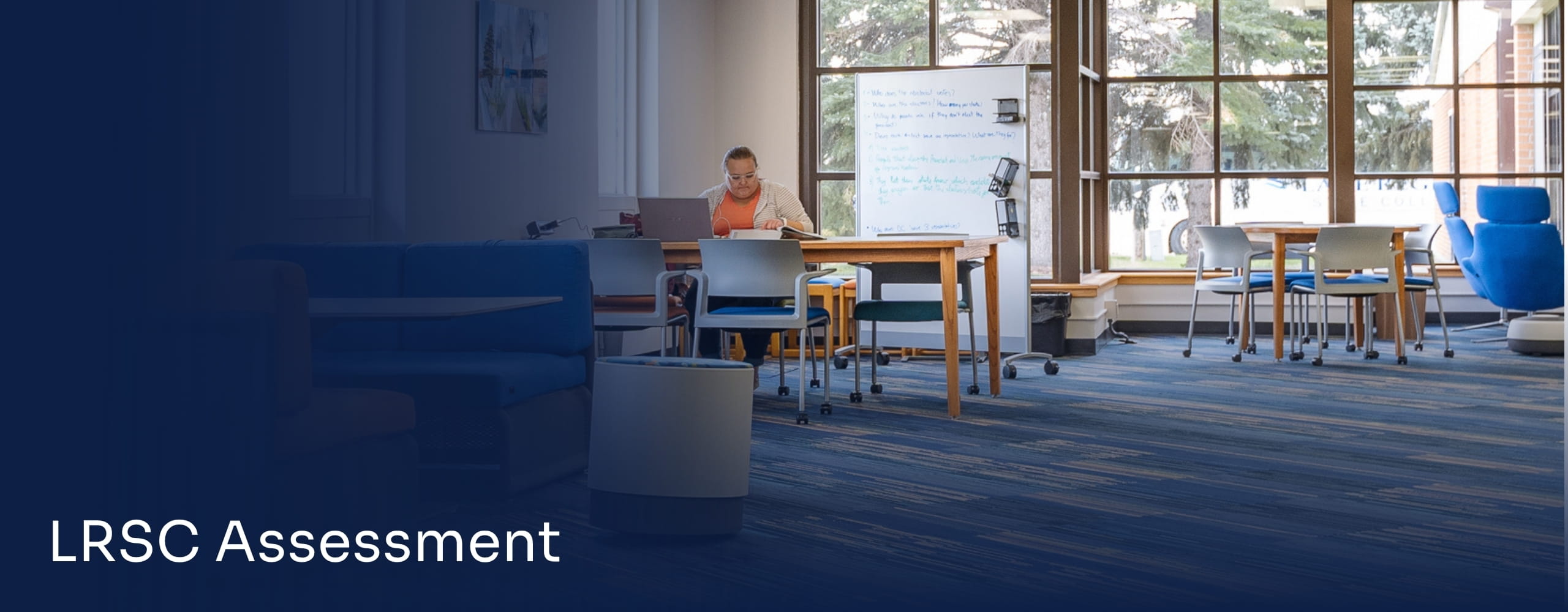 Student studying at a table in a campus learning space.