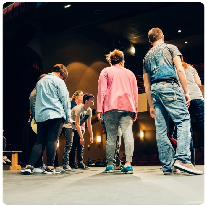 Students gather on stage during a theater rehearsal.