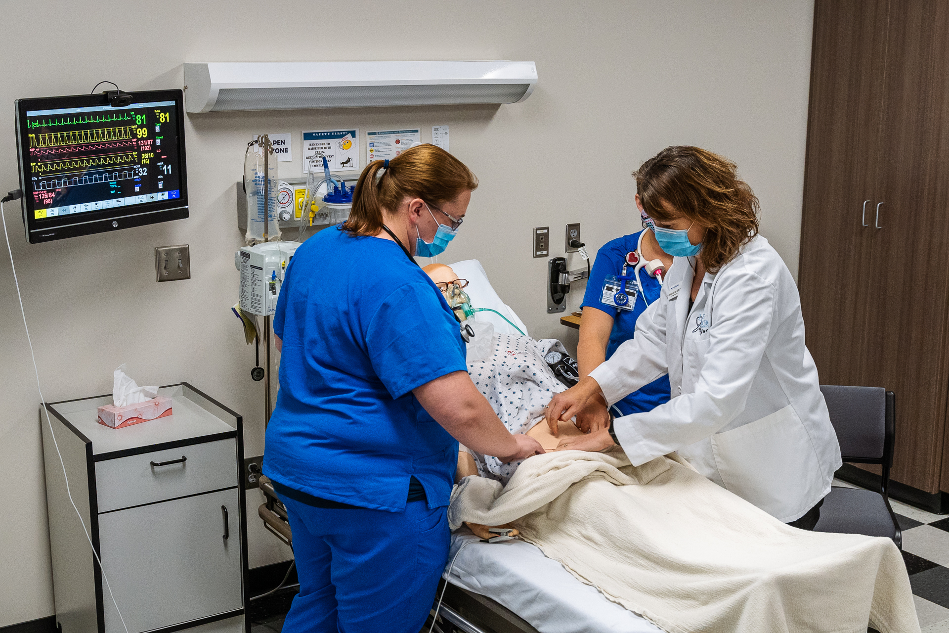 Nursing faculty work with student in simulation lab