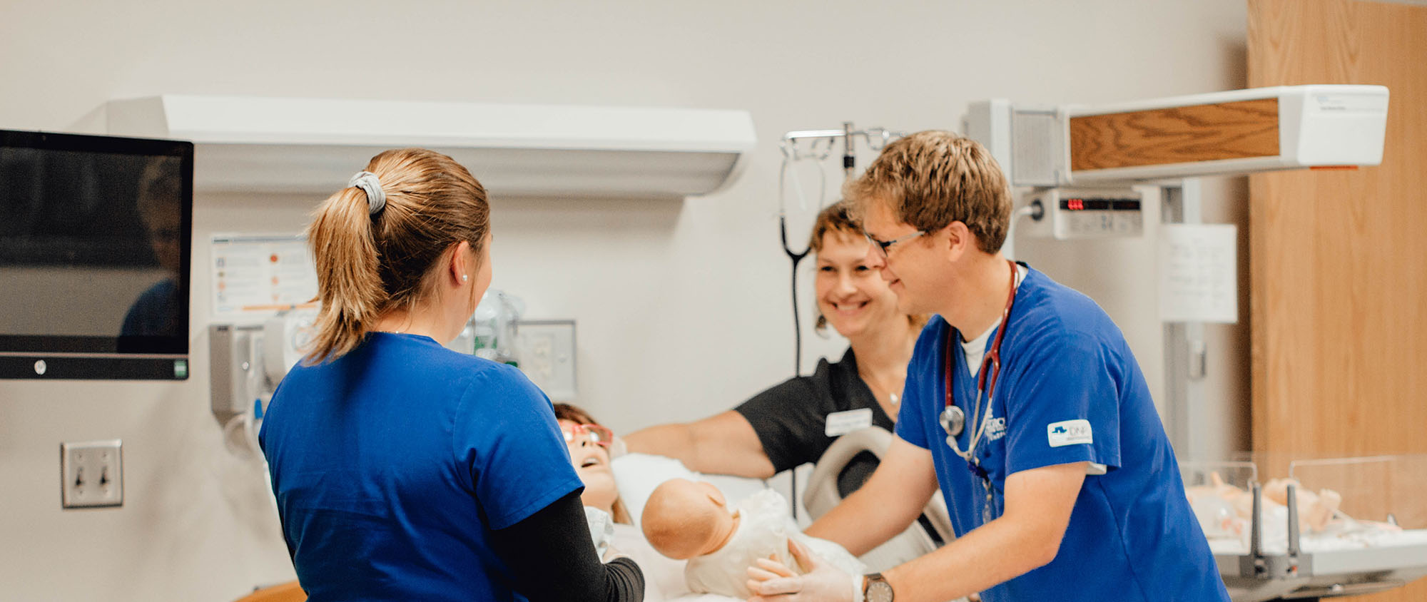 two nursing students and instructor working in sim lab