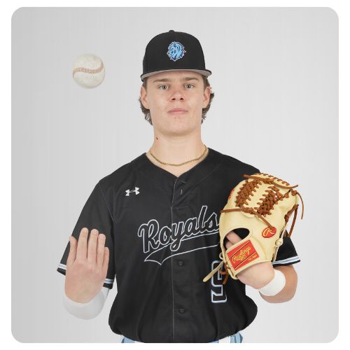 Student athlete wearing a black Lake Region State College Royals baseball uniform, holding a baseball glove while tossing a baseball in a studio setting against a light background.