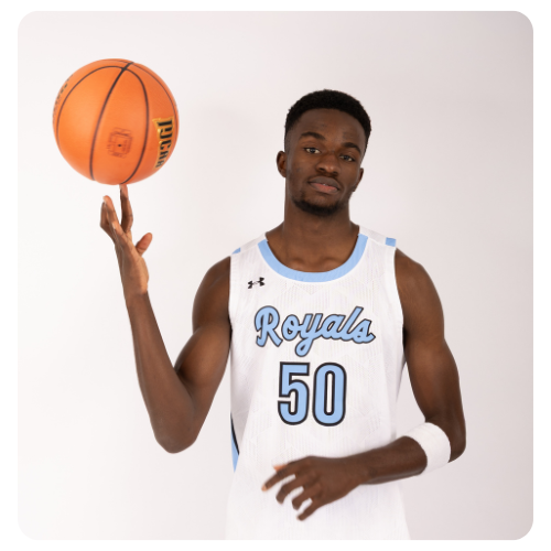 Student athlete wearing a white Lake Region State College Royals basketball jersey with the number 50, spinning a basketball on one finger in a studio setting against a light background.