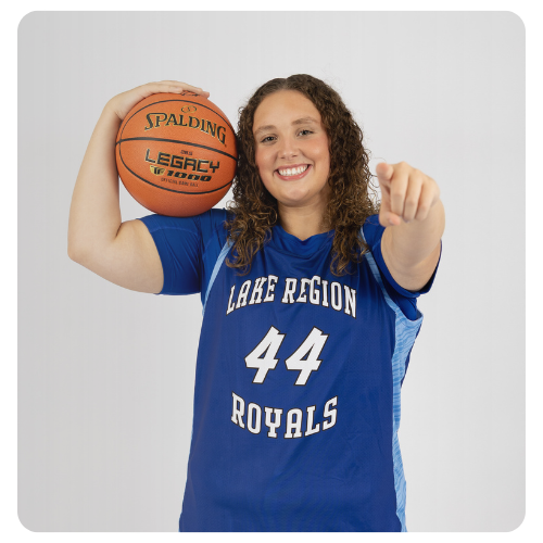 Lake Region State College Royals basketball player wearing a blue jersey with number 44, holding a basketball on one shoulder. 