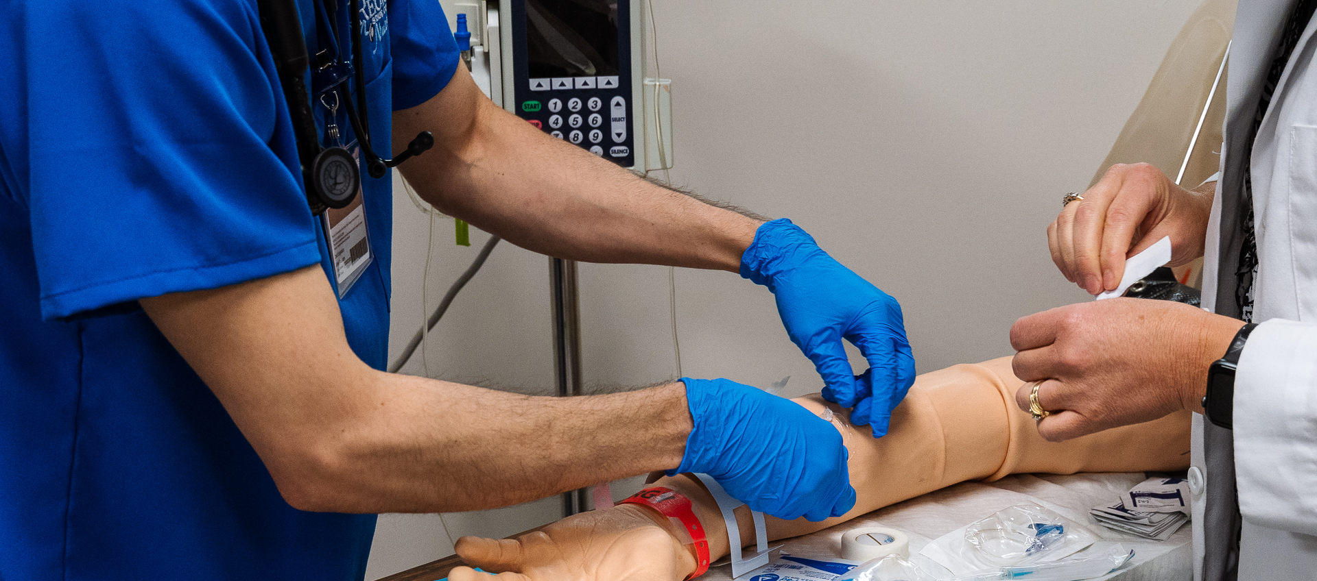 student nurse and instructor practice iv on mannequin