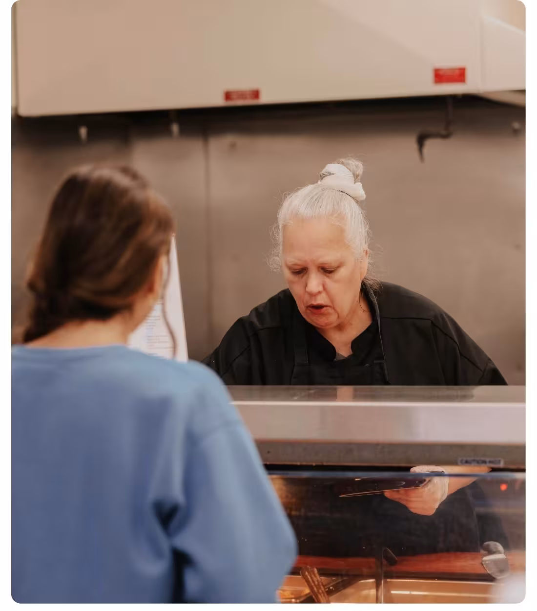 Dining services staff member serves food to a student at the LRSC dining counter.