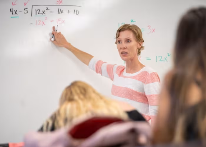 Female instructor pointing at a math problem. 