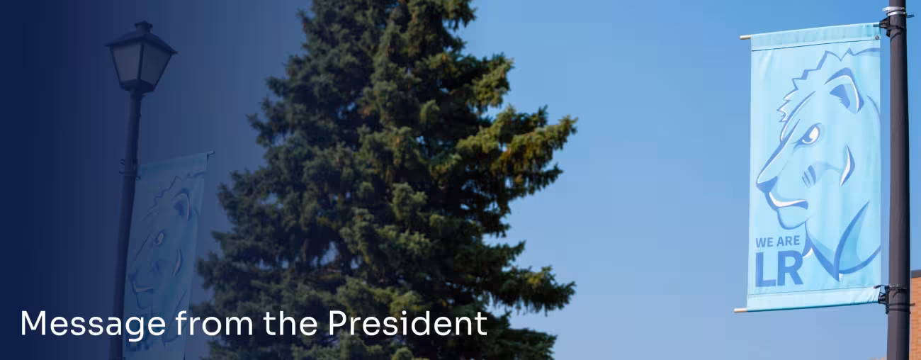 LRSC campus banner displayed beside a large evergreen tree.