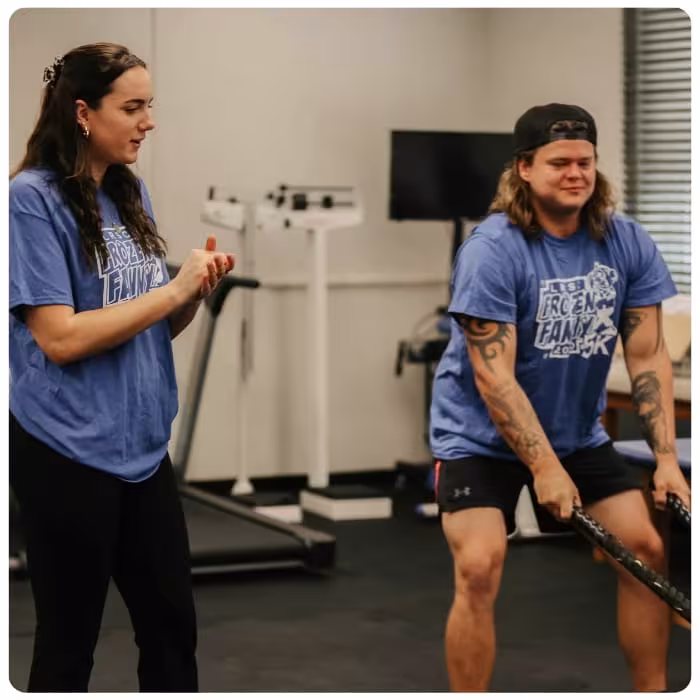 Student exercises with battle ropes during a fitness class.