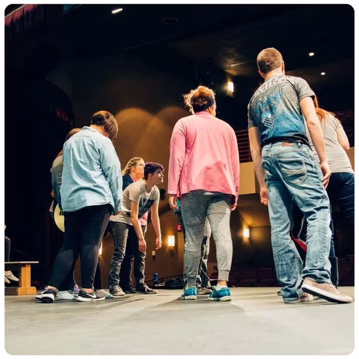 Students gather on stage during a theater rehearsal.