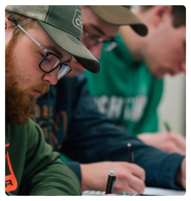 Students working on a classroom assignment, writing notes and focusing on course materials.