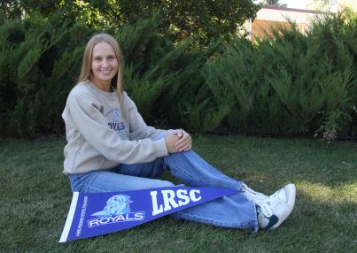 LRSC graduate Kassidy Hart poses on lawn with LRSC pennant