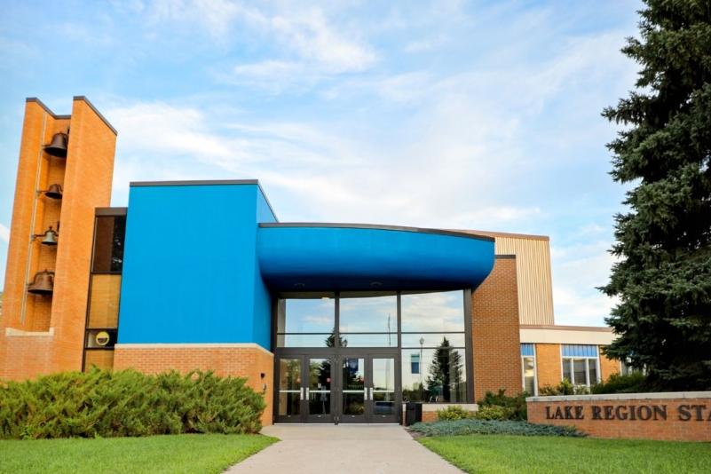 Lake Region State College campus building entrance with blue facade and brick college sign.
