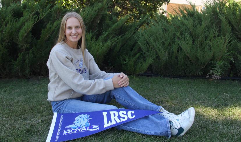 LRSC graduate Kassidy Hart poses on lawn with LRSC pennant